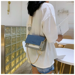 Détail du sac bandoulière bicolore avec rabat en daim bleu et chaîne dorée élégante