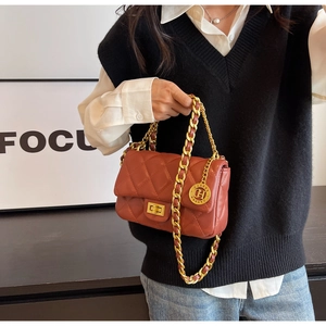 Detail of red quilted crossbody bag with golden chain strap and round metal logo charm
