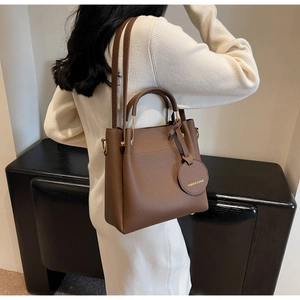 Brown textured bucket bag shown from a side view on model with double straps