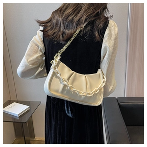 Close-up of cream ruched cloud bag with stylish chunky chain and gold shoulder strap