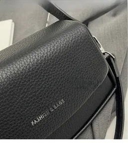 Détail de la texture cuir grainé noir et logo argenté sur le petit sac carré à bandoulière