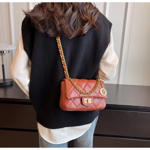 Detail of red-brown quilted leather shoulder bag with golden chain strap and swivel lock