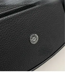 Détail du fermoir magnétique argenté sur un sac à main en cuir noir grainé