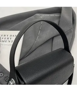 Détail d'un sac à main noir en cuir grainé avec poignée large et boucle métallique argentée
