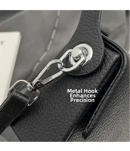 Détail du crochet rotatif en métal argenté et du cuir noir grainé du sac à bandoulière