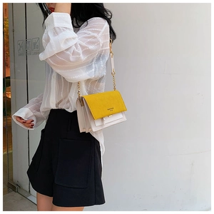 Détail du sac à bandoulière bicolore jaune et beige avec chaîne dorée et fermoir