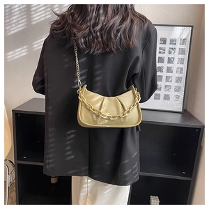 Close-up of beige ruched cloud bag with metallic chain detail and artistic shadow