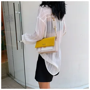Détail du sac bandoulière bicolore avec anneau en métal doré et chaîne porté par un modèle