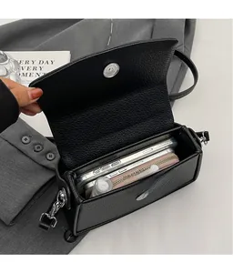 Détail montrant l'intérieur spacieux du sac à bandoulière en cuir noir grainé