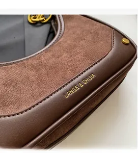 Détail du sac croissant en cuir marron avec chaîne dorée et logo de marque gravé