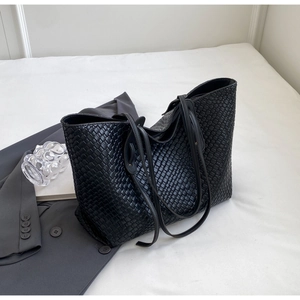 Detailed view of black woven tote bag featuring large capacity and premium PU leather texture