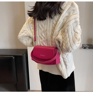 Sac bandoulière carré magenta texture litchi porté par un mannequin en tenue décontractée