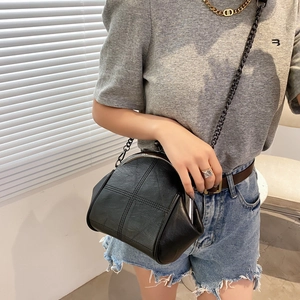 Black vintage shell crossbody bag with cross stitching and metal chain strap on model