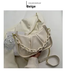 Detail of beige pleated cloud bag featuring chunky white chain and gold metal strap