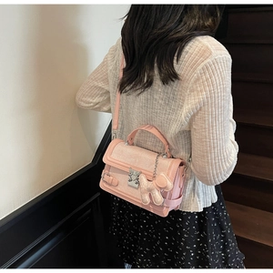 Pink leather handbag with silver clasp and cute puppy charm shown on female model