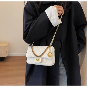 Close-up of white quilted rhombus pattern handbag with gold metal lock and chain strap