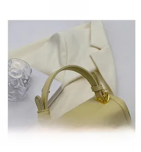 Detail of the comfortable handle on a yellow leather handbag with gold metal hardware
