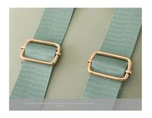 Detail of mint green nylon strap with gold adjustable metal buckles on a quilted backpack