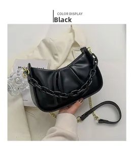 Detail view of black dumpling bag with textured pleats and decorative matte chain strap