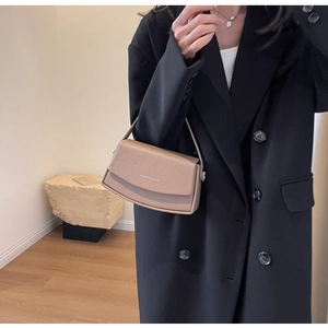 Détail d'un sac bandoulière beige en cuir grainé avec logo argenté et rabat enveloppe