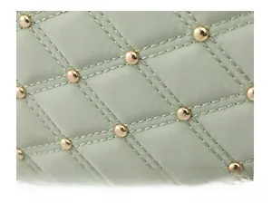 Macro detail of quilted nylon backpack with metallic studs and light green finish