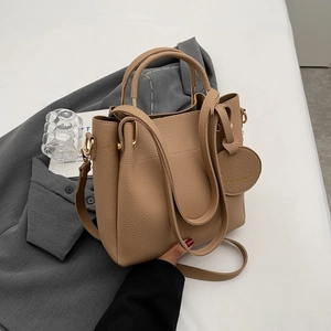 Minimalist camel pebbled leather bucket bag with gold hardware and shoulder strap