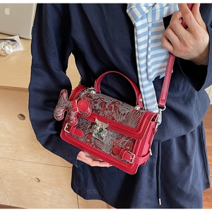Detail of red handbag with Chinese style silver embroidery and cute puppy charm