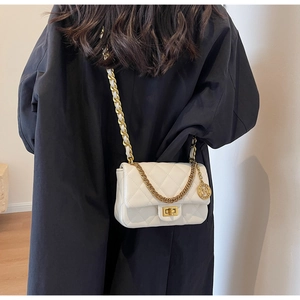 Close-up of beige quilted leather shoulder bag with gold chain and metal logo tag