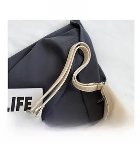 Detail of creamy white crossbody bag showing wide strap and silver metal buckle