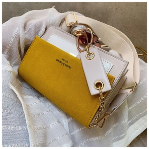 Détail du sac bandoulière en daim jaune et cuir blanc avec chaîne dorée élégante