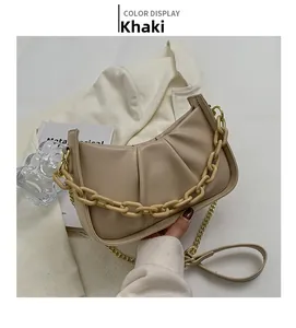 Khaki pleated cloud bag with resin chain and gold strap on white blazer display