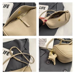Detail view of beige lychee leather dumpling bag with woven strap and elephant charm