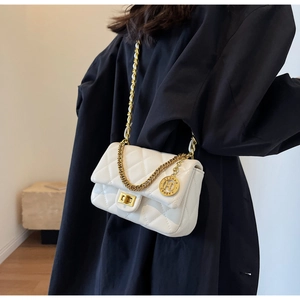 Detail of white quilted crossbody bag with golden chain strap and letter H logo charm