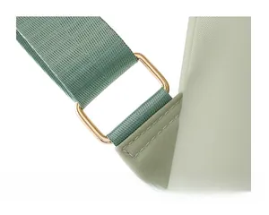 Close-up of light green nylon shoulder strap with reinforced stitching and gold buckle