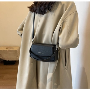 Détail du petit sac carré en cuir grainé noir avec logo argenté et bandoulière réglable