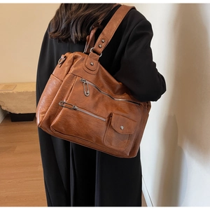 Detailed view of brown vintage leather crossbody bag with multiple zipper pockets