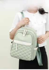 Detail of light green quilted nylon backpack with gold studs shown on model