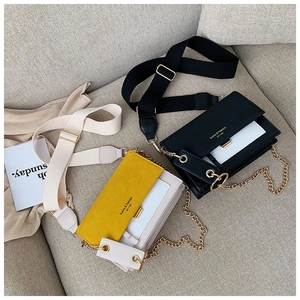 Détail de sacs bandoulière avec larges bretelles en tissu et chaînes dorées sur un canapé