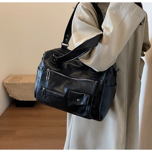 Detail view of large capacity black leather travel bag with multiple functional zipper pockets