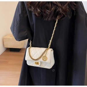 Detail of white quilted crossbody bag with golden chain strap and brand charm pendant