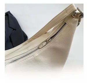 Detail of silver metallic zipper on cream lychee pattern leather handbag for women