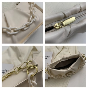 Detail view of beige ruched cloud bag showing chain straps and zipper closure