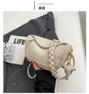 Detail of cream white dumpling bag with woven handle and elephant charm ornament