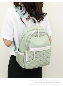 Detail of light green quilted nylon backpack showing diamond stitching and gold rivets
