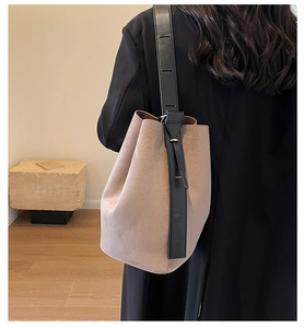 Détail du sac seau en daim beige minimaliste porté par un mannequin en intérieur