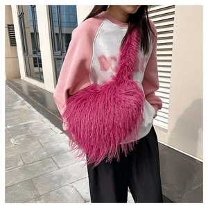 Detail of soft rose red faux fur crossbody bag with plush texture on model outdoors