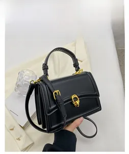 Detail view of black leather handbag featuring a gold ring clasp and adjustable strap