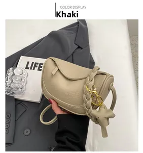 Detail of khaki pebbled leather shoulder bag with woven strap and elephant charm