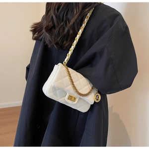 Detail of white quilted crossbody bag with golden chain strap and rotary lock buckle