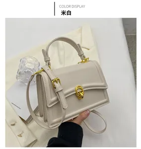 Detail view of structured cream faux leather crossbody bag with gold-tone hardware